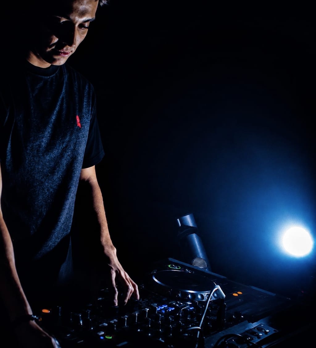 DJ Nicolai Pedersen mixing on a controller in a dark venue with blue backlight